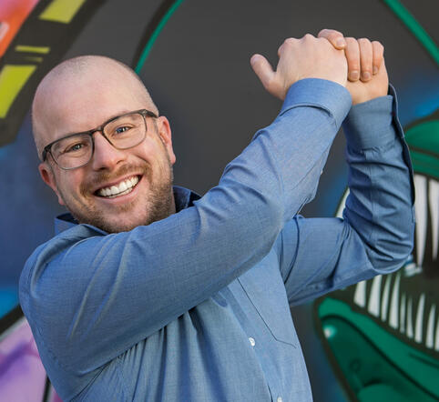 Man in a blue shirt smiling while making a golf swing